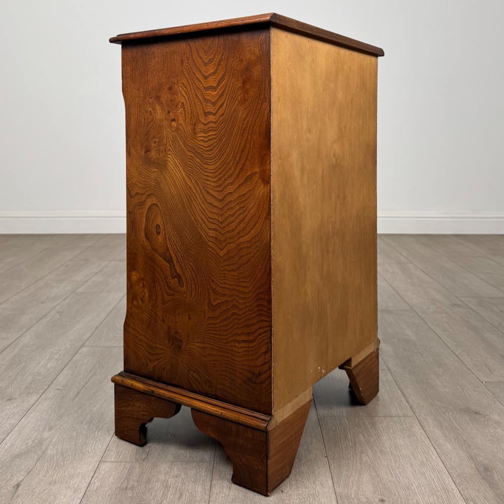 A small 20th-century serpentine chest of drawers with four drawers featuring burr walnut veneer, brass drop handles, and bracket feet. View IV
