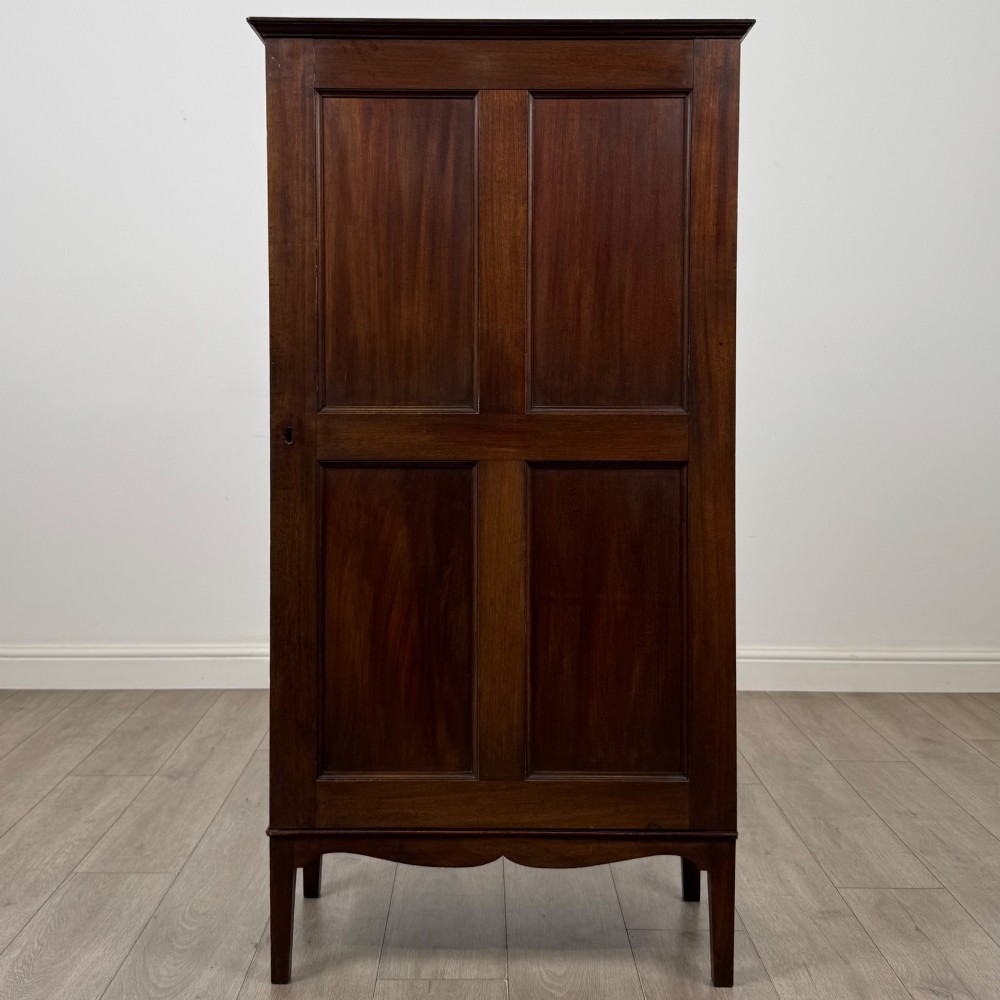 An 18th-century Georgian dark mahogany standing cabinet featuring two tall recessed field-panel doors, a subtle curved apron, and square tapered legs.