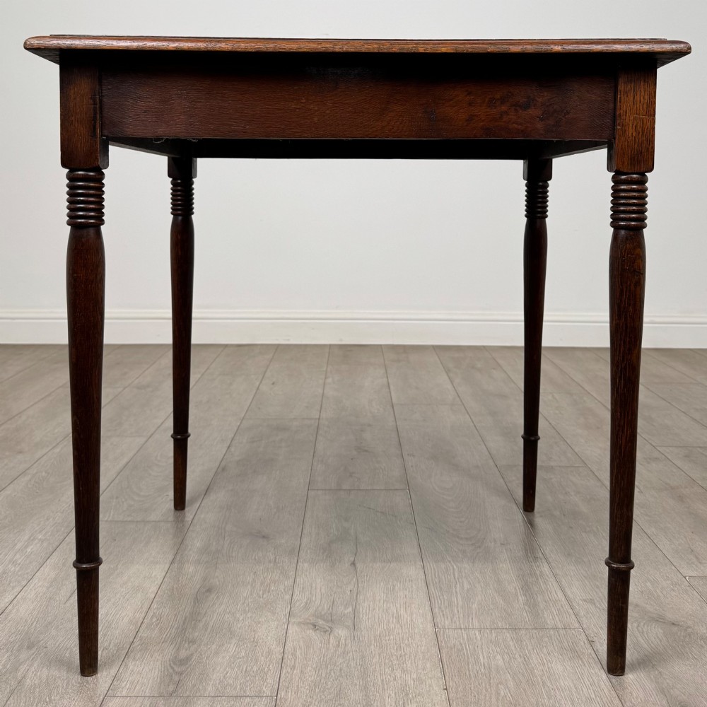 An antique Edwardian dark oak side table featuring slender turned legs with ring details and a smooth square top surface.