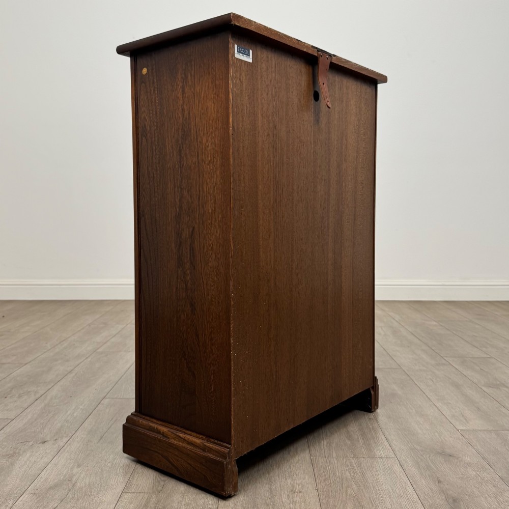A small vintage dark oak bookcase featuring three open shelves, decorative carved detailing along the frieze and side uprights, and a solid plinth base. View V