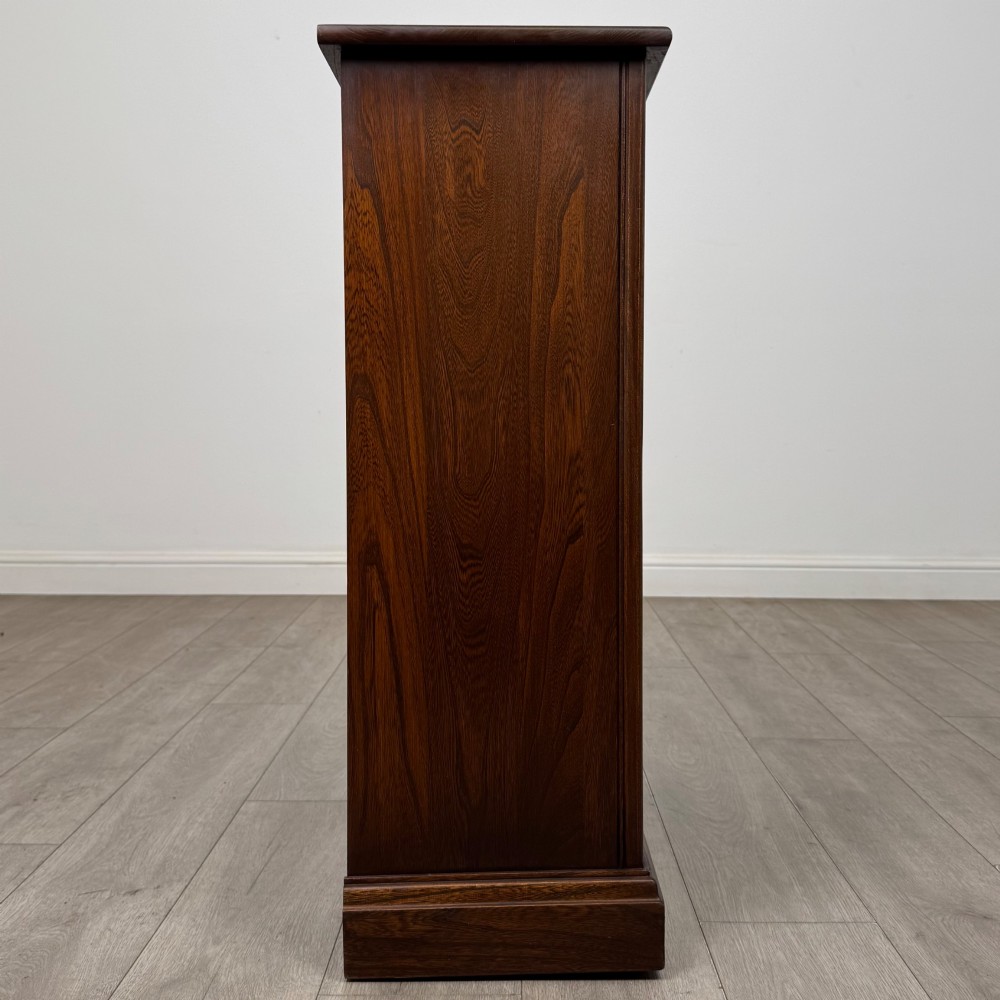 A small vintage dark oak bookcase featuring three open shelves, decorative carved detailing along the frieze and side uprights, and a solid plinth base. View VIII