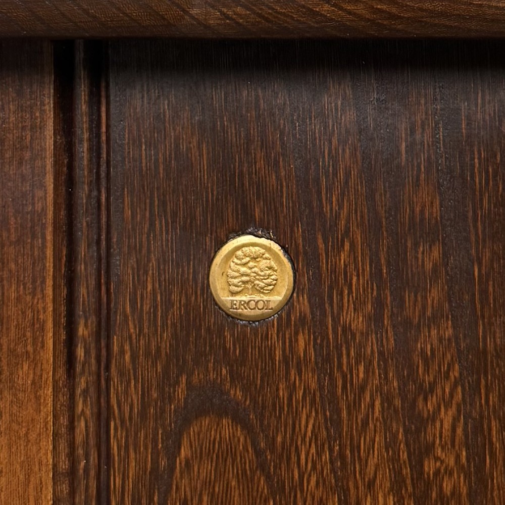 A small vintage dark oak bookcase featuring three open shelves, decorative carved detailing along the frieze and side uprights, and a solid plinth base. View XI