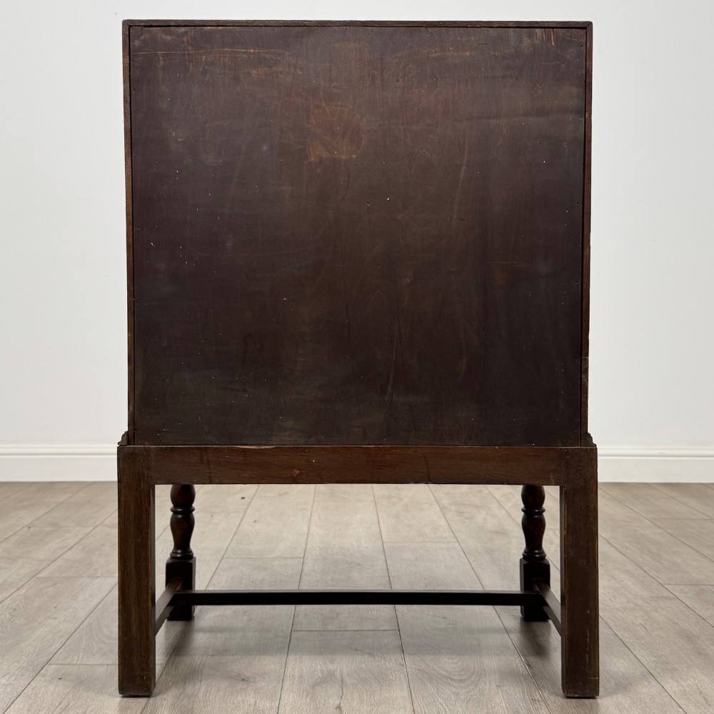An Edwardian dark oak writing bureau featuring a sloped drop-down lid, two lower drawers with teardrop handles, and turned legs connected by stretchers. View VI