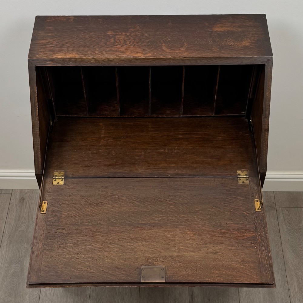 An Edwardian dark oak writing bureau featuring a sloped drop-down lid, two lower drawers with teardrop handles, and turned legs connected by stretchers. View XI