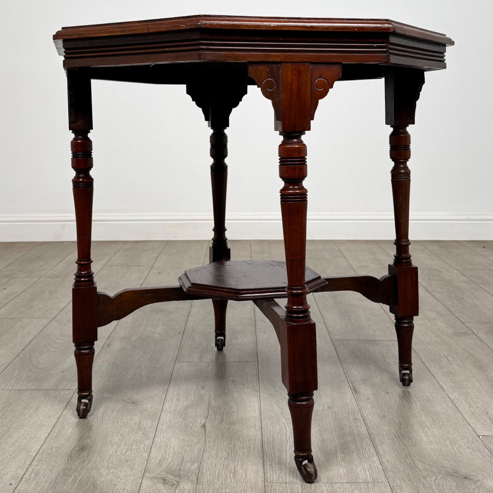 An antique mahogany side table featuring an octagonal top, turned legs with castors, and a lower octagonal tier shelf. View II