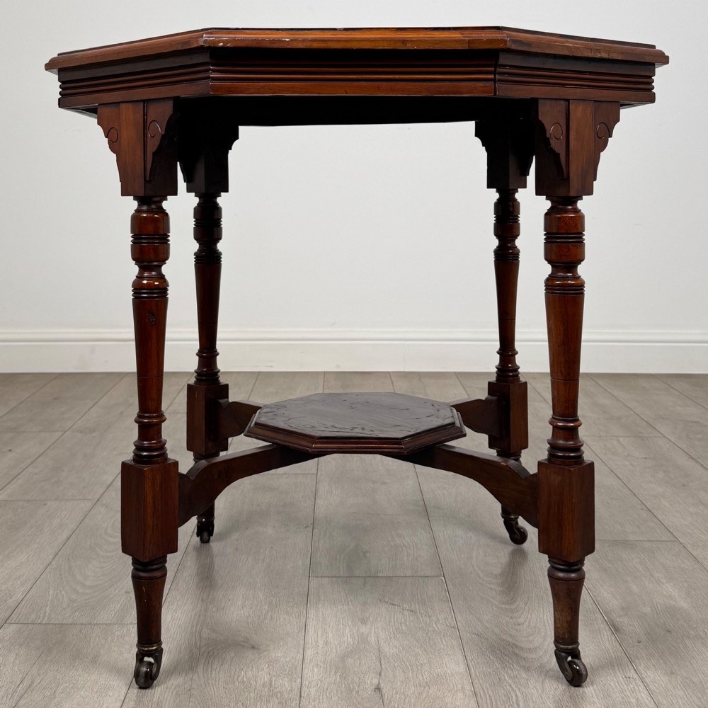 An antique mahogany side table featuring an octagonal top, turned legs with castors, and a lower octagonal tier shelf. View V