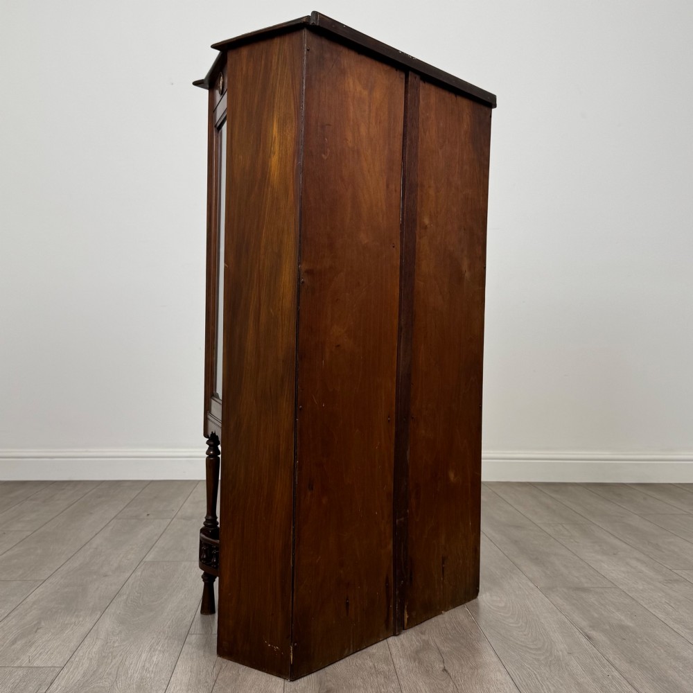 An antique walnut display cabinet featuring glazed door and side panels, decorative inlay along the frieze, and an open lower shelf resting on turned front legs. View V