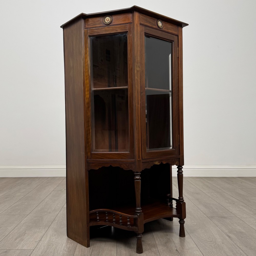 An antique walnut display cabinet featuring glazed door and side panels, decorative inlay along the frieze, and an open lower shelf resting on turned front legs. View IX