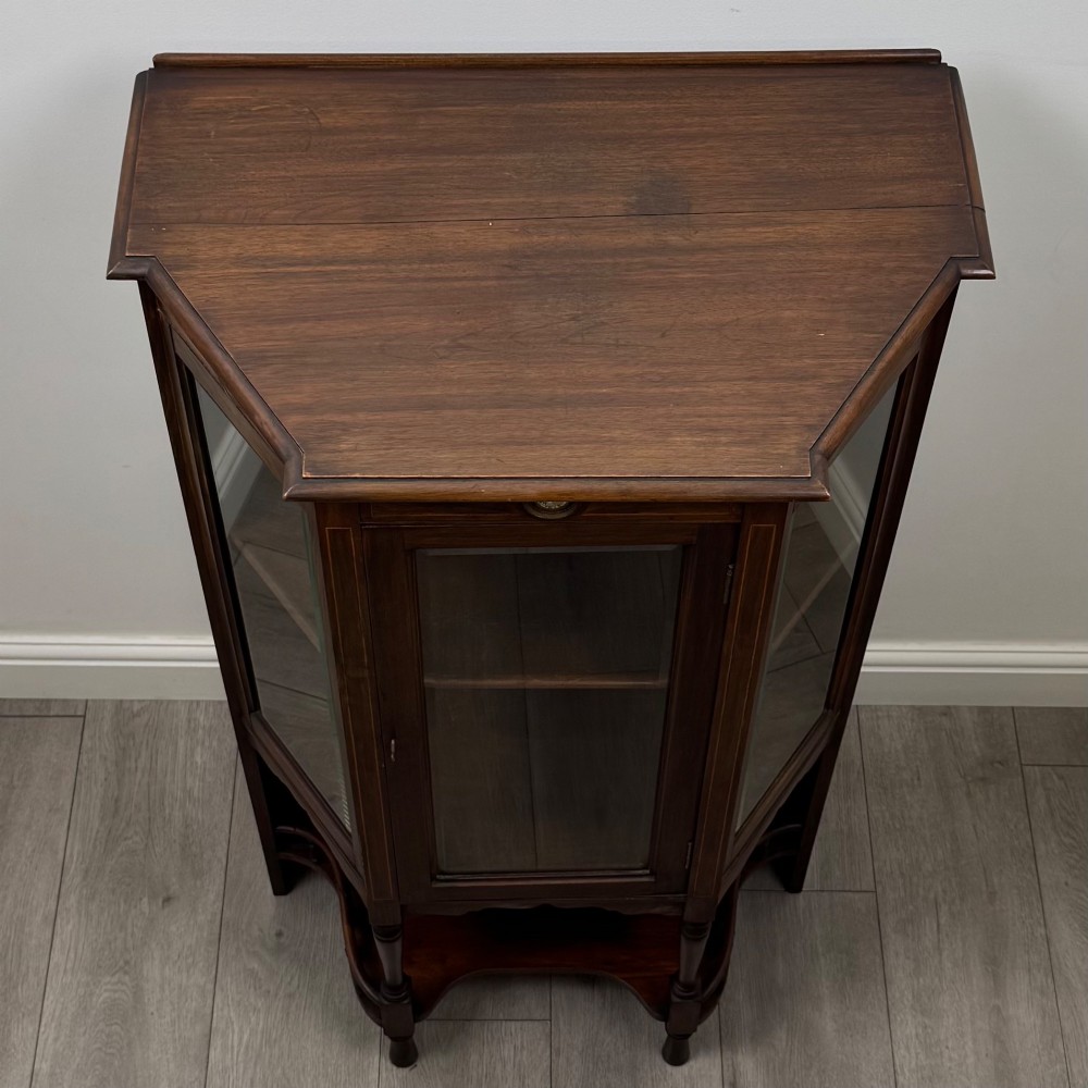 An antique walnut display cabinet featuring glazed door and side panels, decorative inlay along the frieze, and an open lower shelf resting on turned front legs. View X