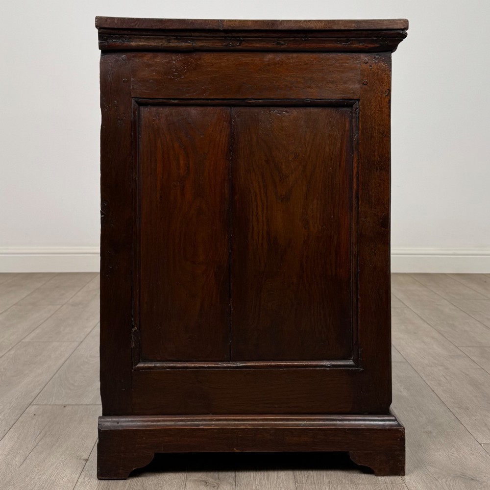 An 18th-century dark oak Georgian chest of drawers featuring four graduated drawers with brass handles and keyhole escutcheons. View VII