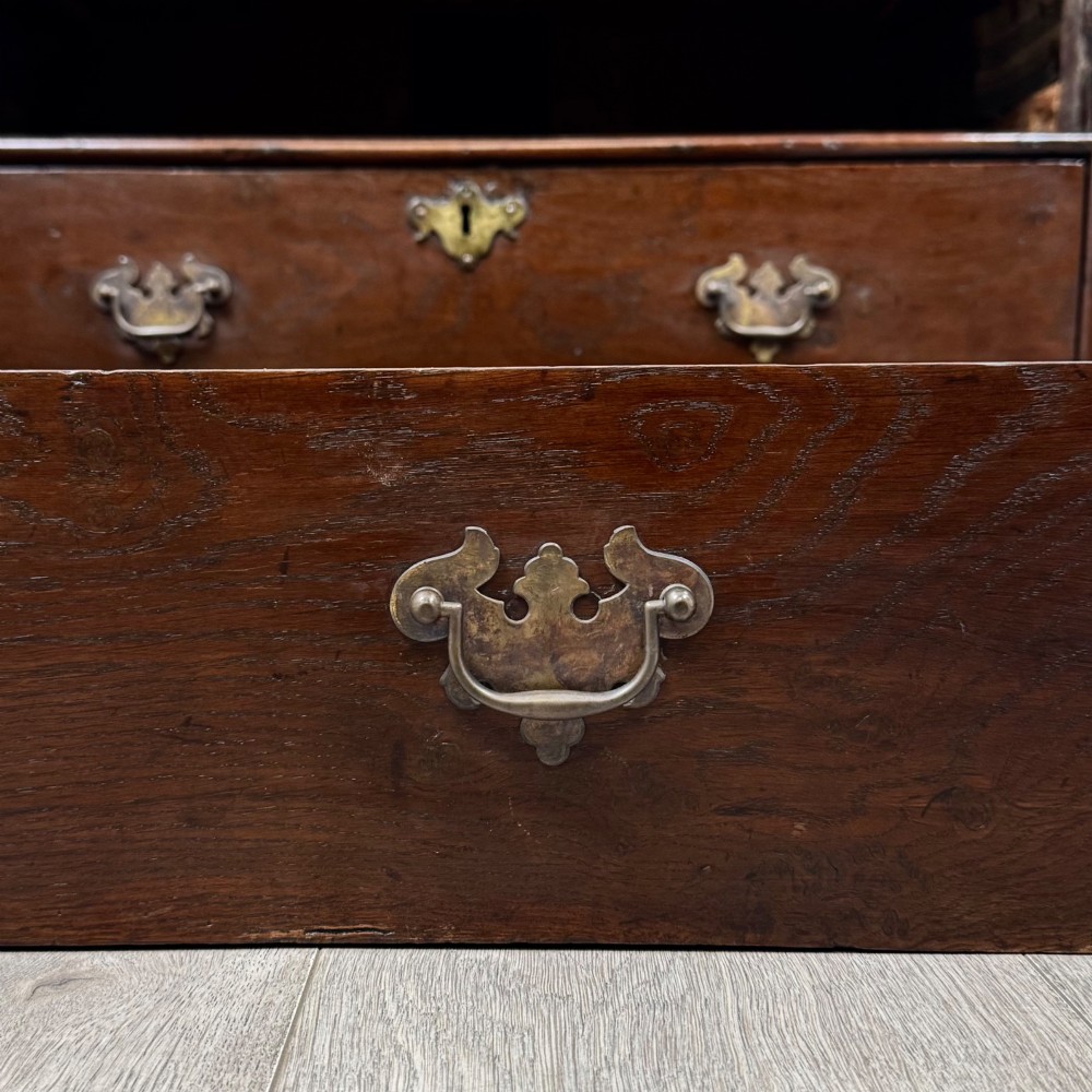 An 18th-century dark oak Georgian chest of drawers featuring four graduated drawers with brass handles and keyhole escutcheons. View XI