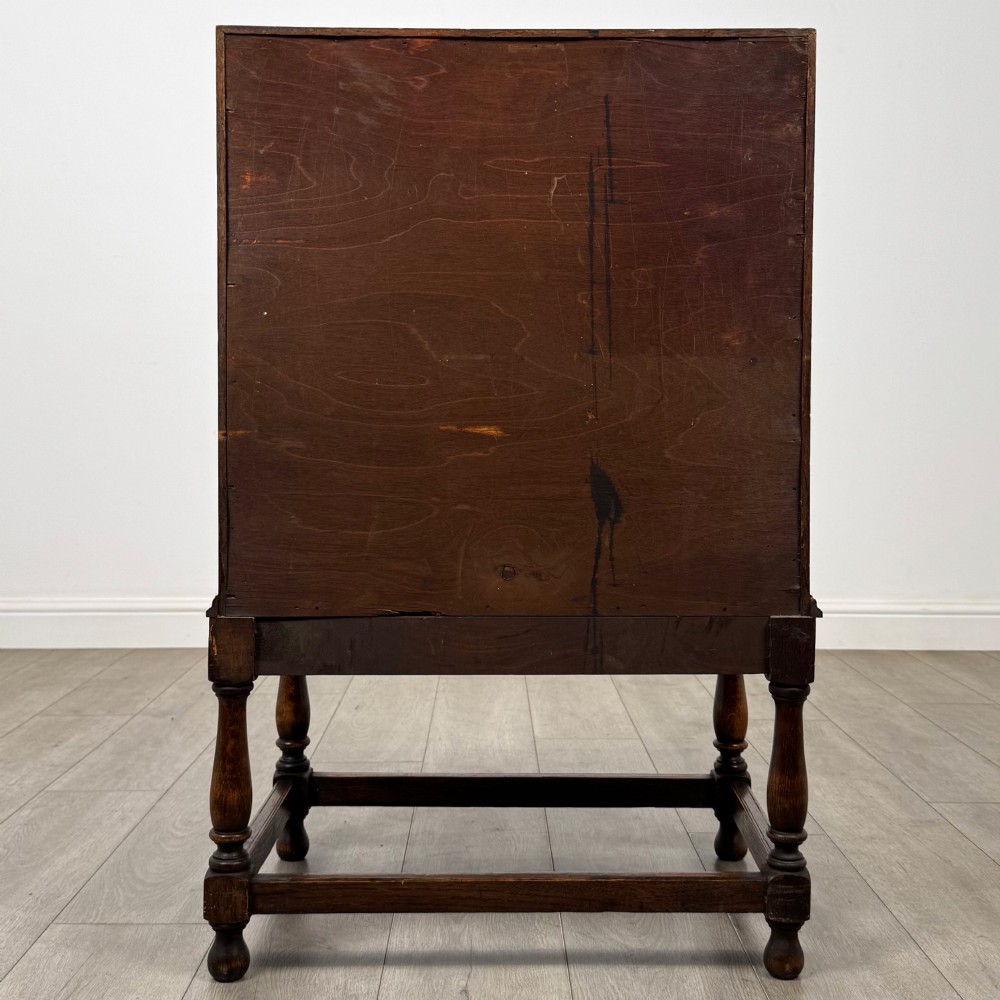 An Edwardian golden oak writing bureau featuring a slant-front writing flap above two drawers with brass teardrop handles, supported on turned legs with a perimeter stretcher. View VI