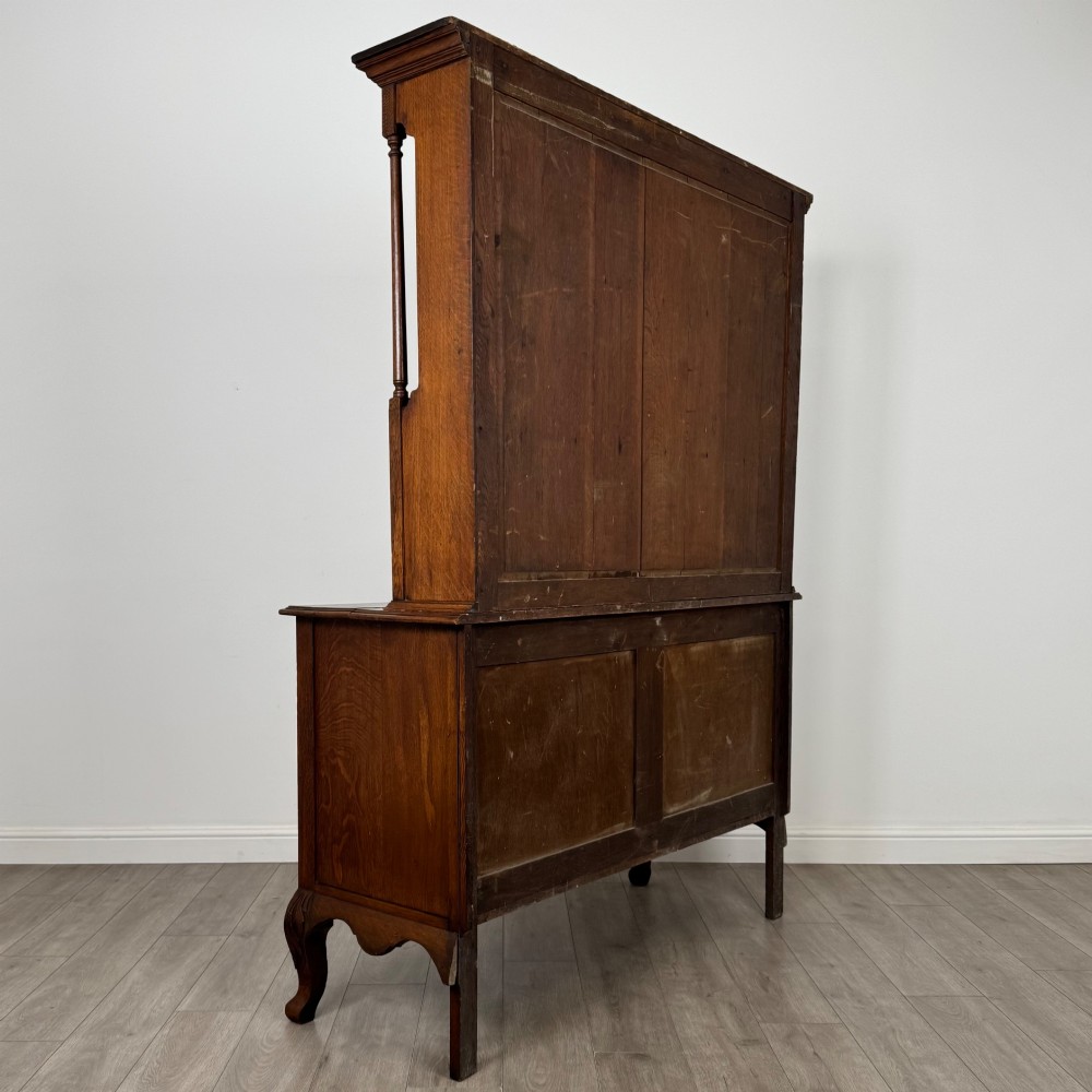 A 20th-century golden oak Welsh dresser featuring a three-tiered open shelf top section over a two-door, two-drawer base with cabriole legs. View V