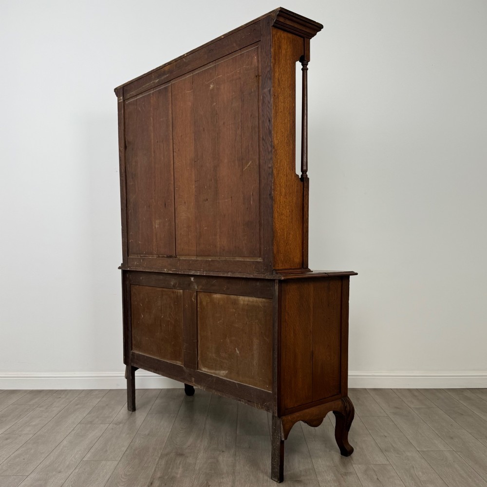 A 20th-century golden oak Welsh dresser featuring a three-tiered open shelf top section over a two-door, two-drawer base with cabriole legs. View VII