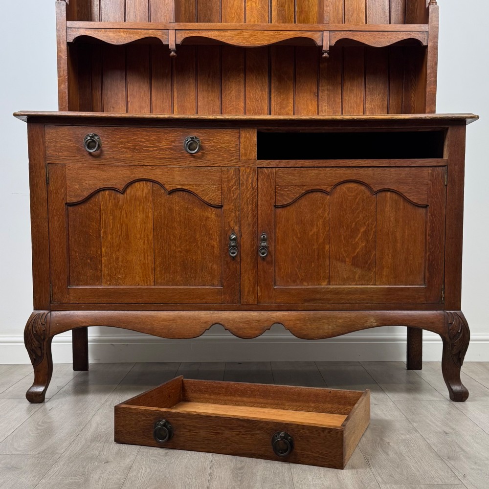 A 20th-century golden oak Welsh dresser featuring a three-tiered open shelf top section over a two-door, two-drawer base with cabriole legs. View XI