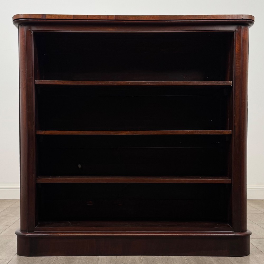 An antique 19th-century Victorian mahogany open bookcase featuring four tier shelves, rounded front corners, and a solid plinth base. View II