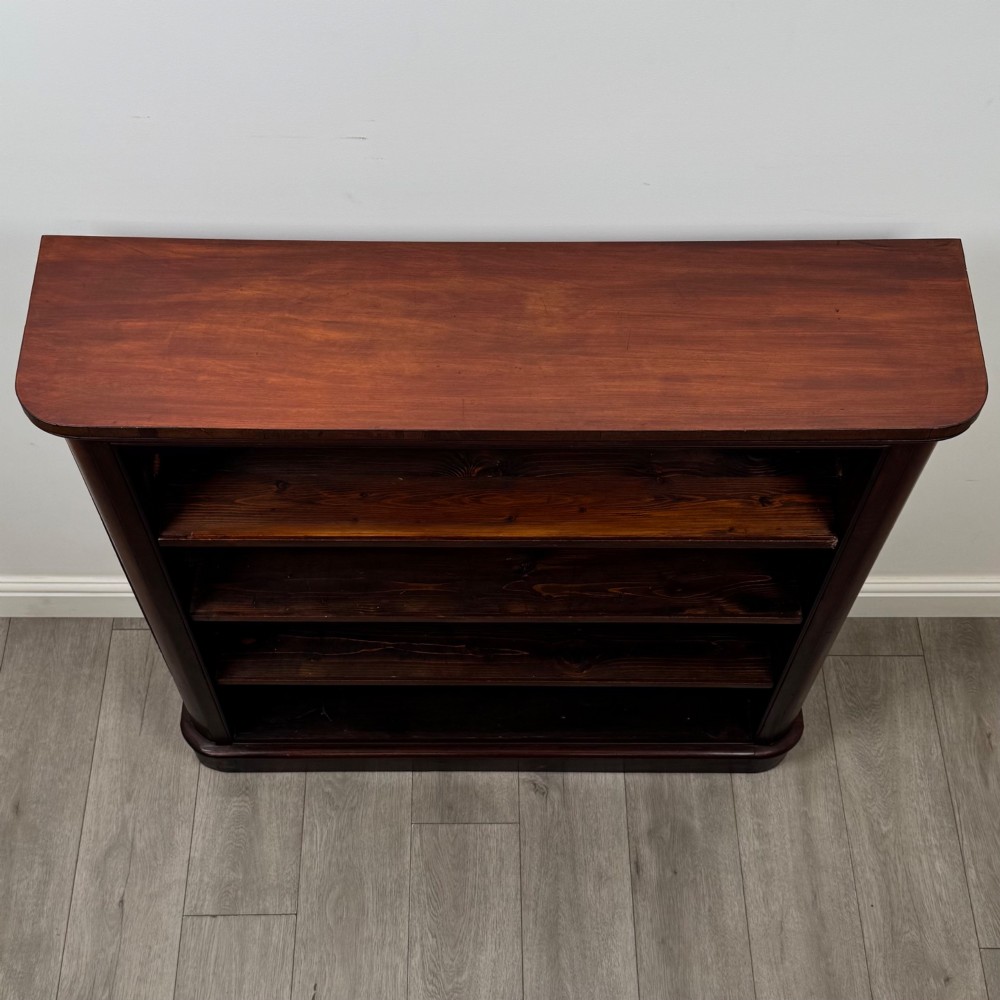 An antique 19th-century Victorian mahogany open bookcase featuring four tier shelves, rounded front corners, and a solid plinth base. View X