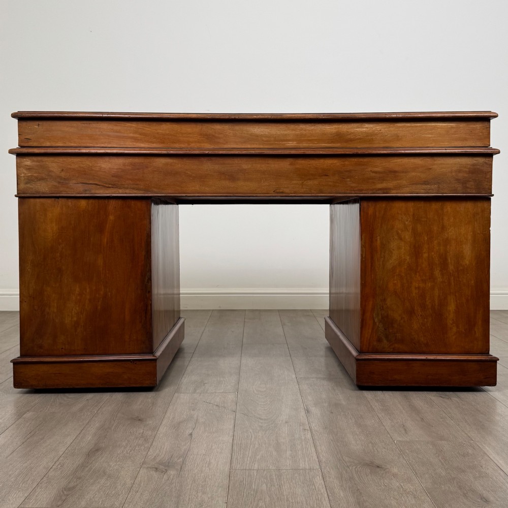 A 19th-century Victorian mahogany Dickens desk featuring a sloped green leather writing top, a raised rear superstructure, and twin pedestals fitted with turned knobs. View V