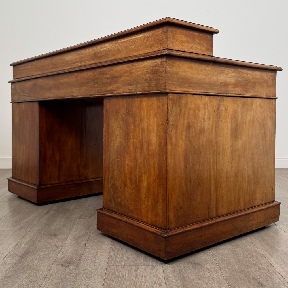 A 19th-century Victorian mahogany Dickens desk featuring a sloped green leather writing top, a raised rear superstructure, and twin pedestals fitted with turned knobs. View VI