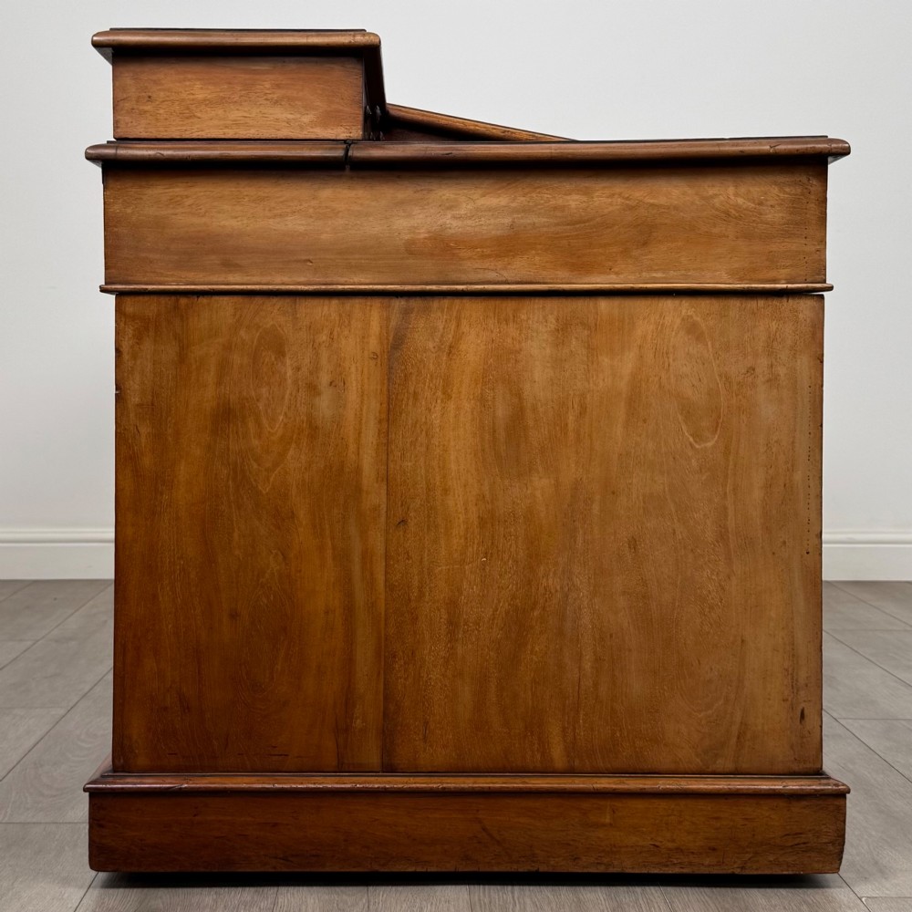 A 19th-century Victorian mahogany Dickens desk featuring a sloped green leather writing top, a raised rear superstructure, and twin pedestals fitted with turned knobs. View VII
