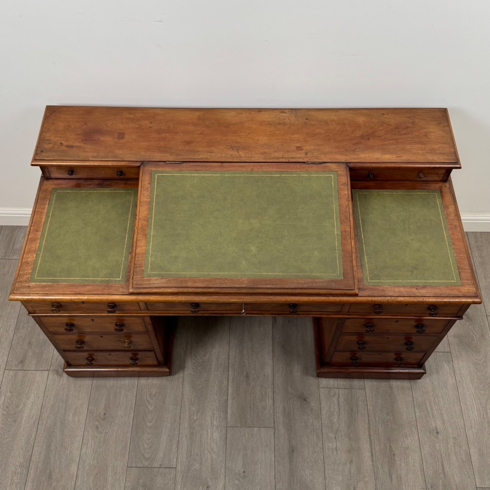 A 19th-century Victorian mahogany Dickens desk featuring a sloped green leather writing top, a raised rear superstructure, and twin pedestals fitted with turned knobs. View IX