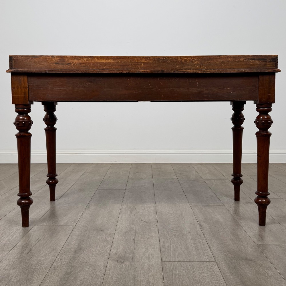 A 19th-century mahogany writing table featuring two frieze drawers with wooden turned handles, standing on four turned legs. View V