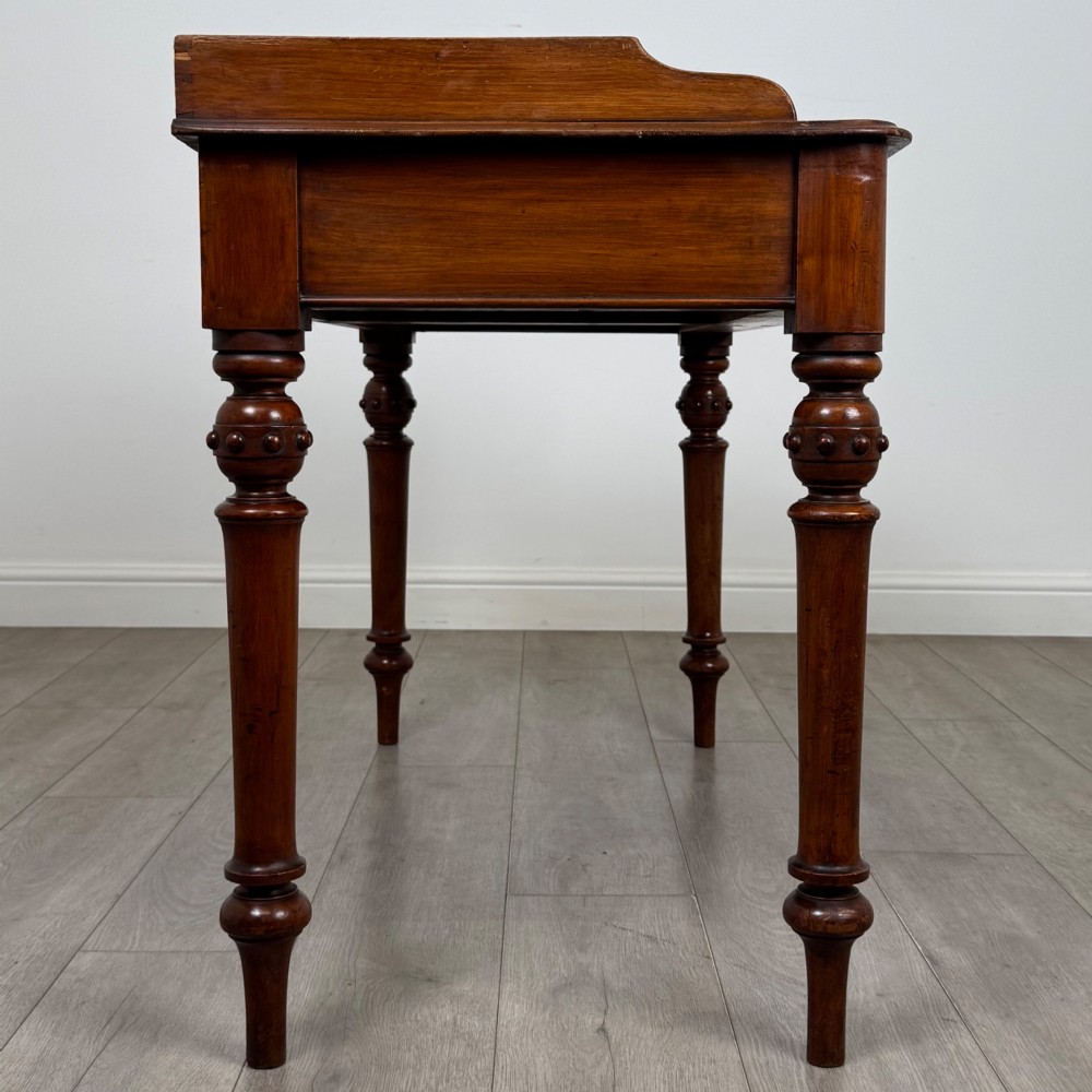 A 19th-century mahogany writing table featuring two frieze drawers with wooden turned handles, standing on four turned legs. View VII