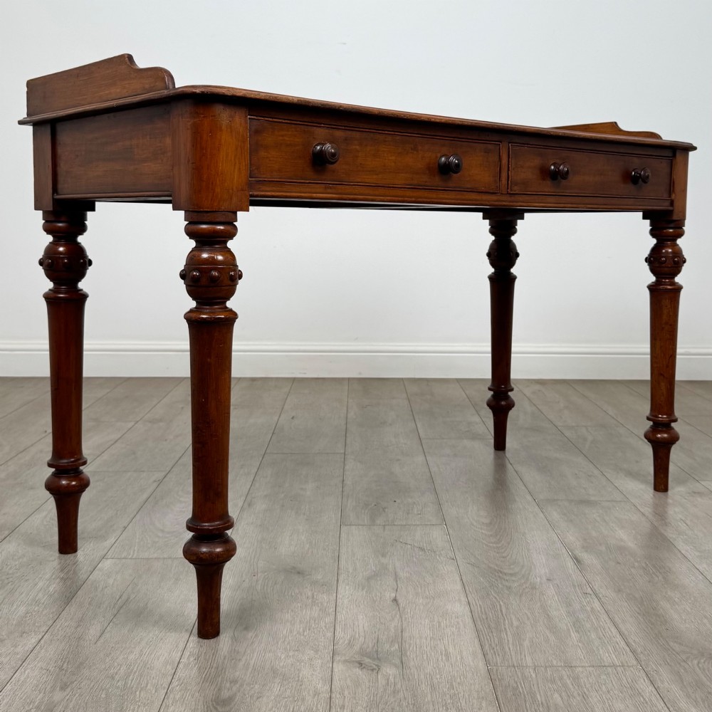 A 19th-century mahogany writing table featuring two frieze drawers with wooden turned handles, standing on four turned legs. View VIII