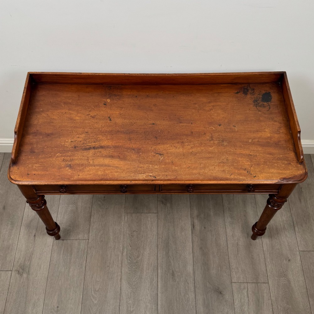 A 19th-century mahogany writing table featuring two frieze drawers with wooden turned handles, standing on four turned legs. View IX