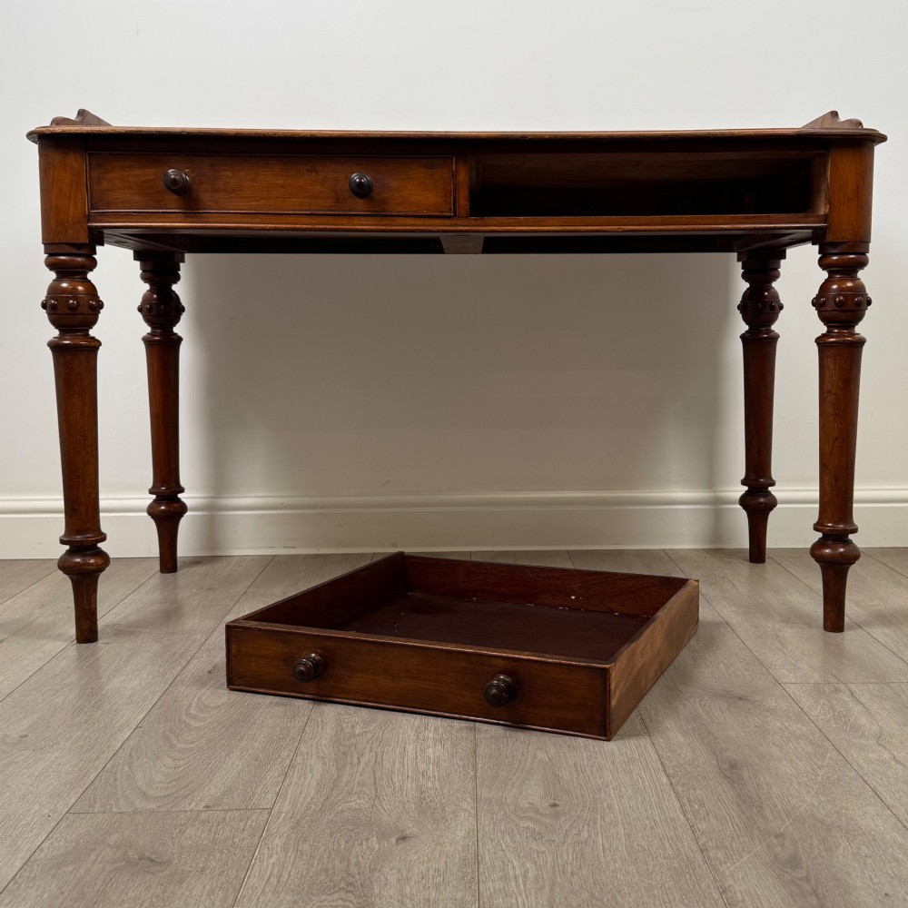 A 19th-century mahogany writing table featuring two frieze drawers with wooden turned handles, standing on four turned legs. View X
