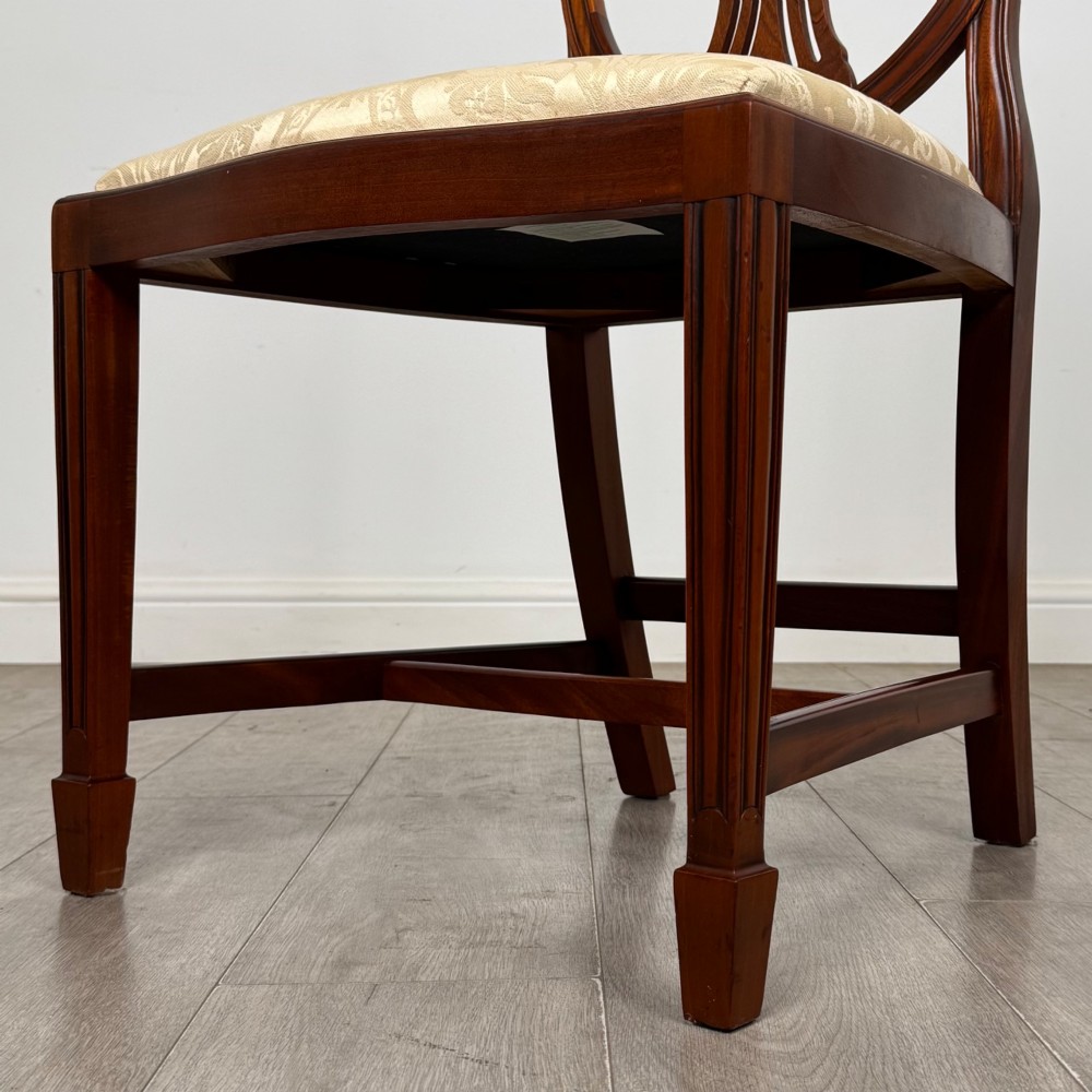 A set of eight mahogany shield back dining chairs featuring intricate pierced back splats and light cream upholstered seats. View V