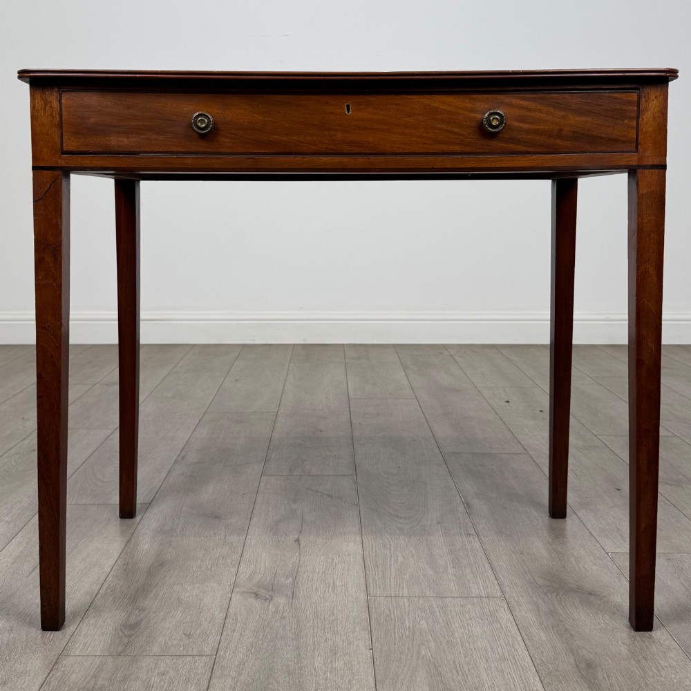 An 18th-century Georgian mahogany writing table featuring a single drawer with brass handles and four square tapered legs.