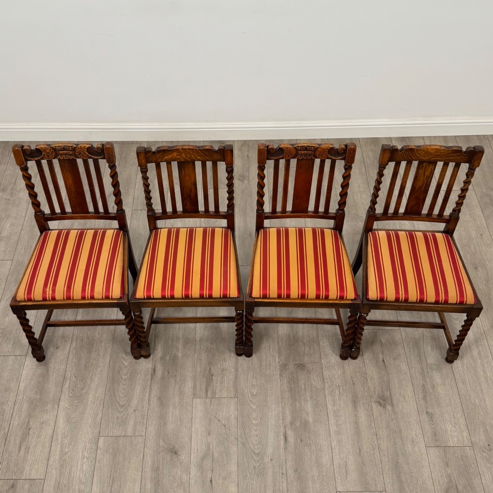 A set of ten early twentieth-century oak dining chairs featuring barley twist turned legs and supports with red and yellow striped upholstered seats. View X