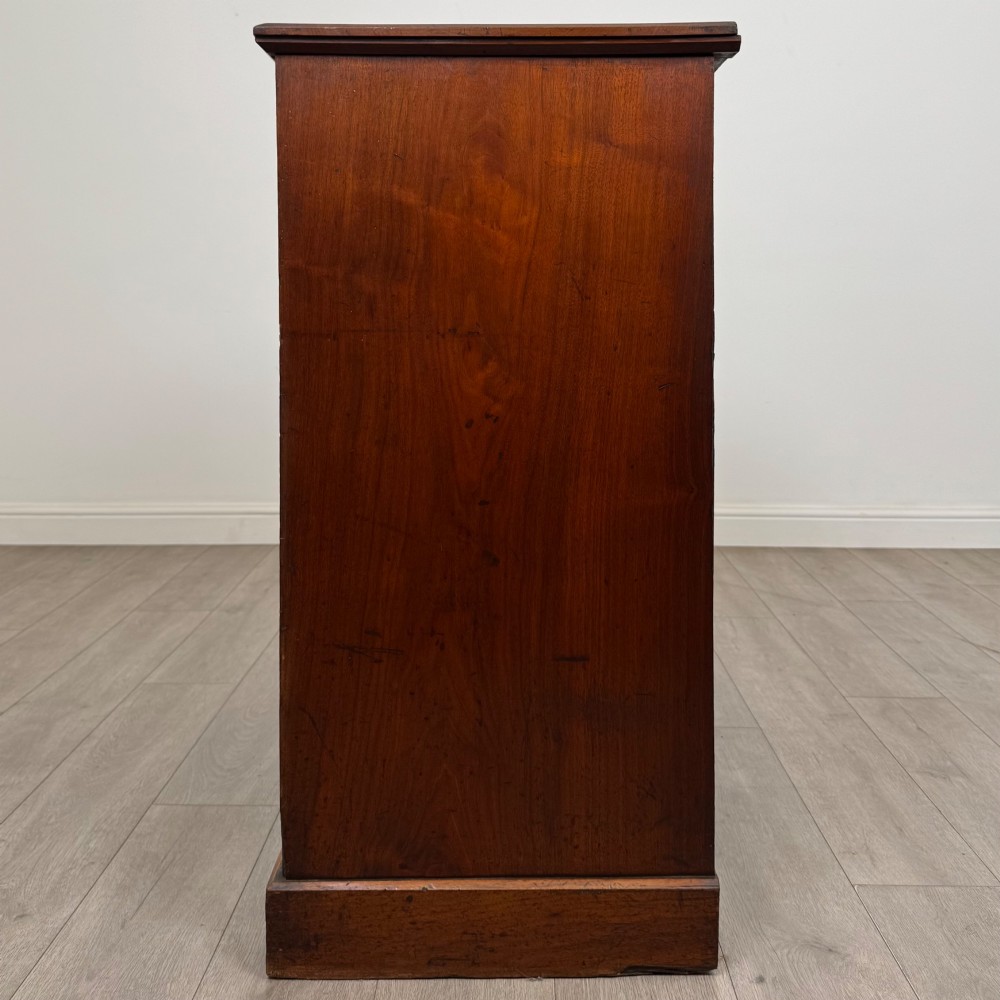 An antique walnut chest of drawers featuring decorative brass handles, reeded top drawer fronts, and a solid plinth base. View III
