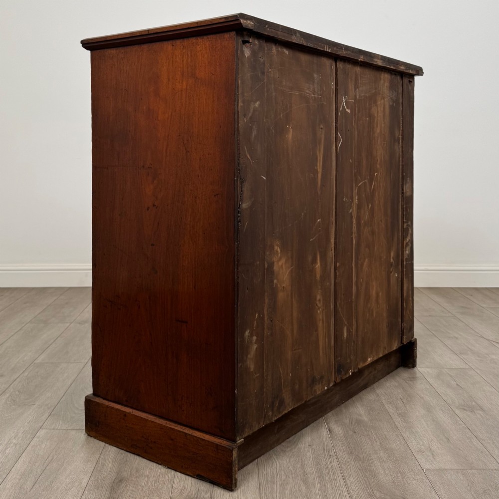 An antique walnut chest of drawers featuring decorative brass handles, reeded top drawer fronts, and a solid plinth base. View IV