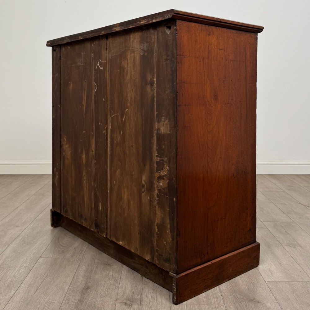 An antique walnut chest of drawers featuring decorative brass handles, reeded top drawer fronts, and a solid plinth base. View VI