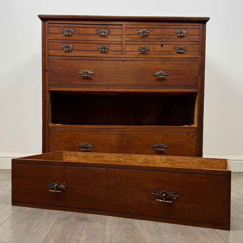 An antique walnut chest of drawers featuring decorative brass handles, reeded top drawer fronts, and a solid plinth base. View X