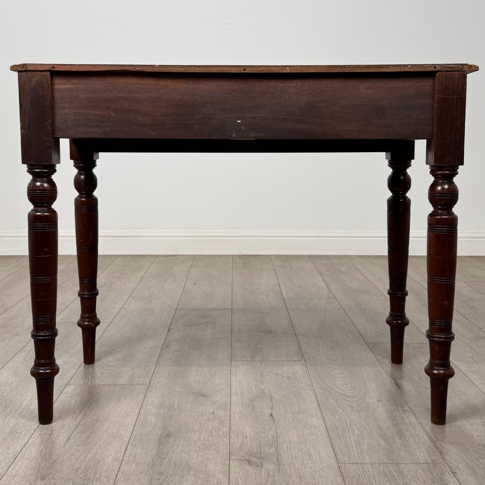 A Victorian mahogany writing table featuring two frieze drawers with wooden knobs and turned reeded legs. View V