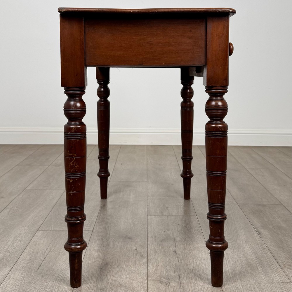 A Victorian mahogany writing table featuring two frieze drawers with wooden knobs and turned reeded legs. View VII