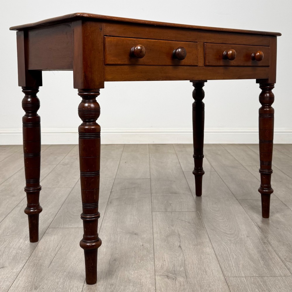 A Victorian mahogany writing table featuring two frieze drawers with wooden knobs and turned reeded legs. View VIII