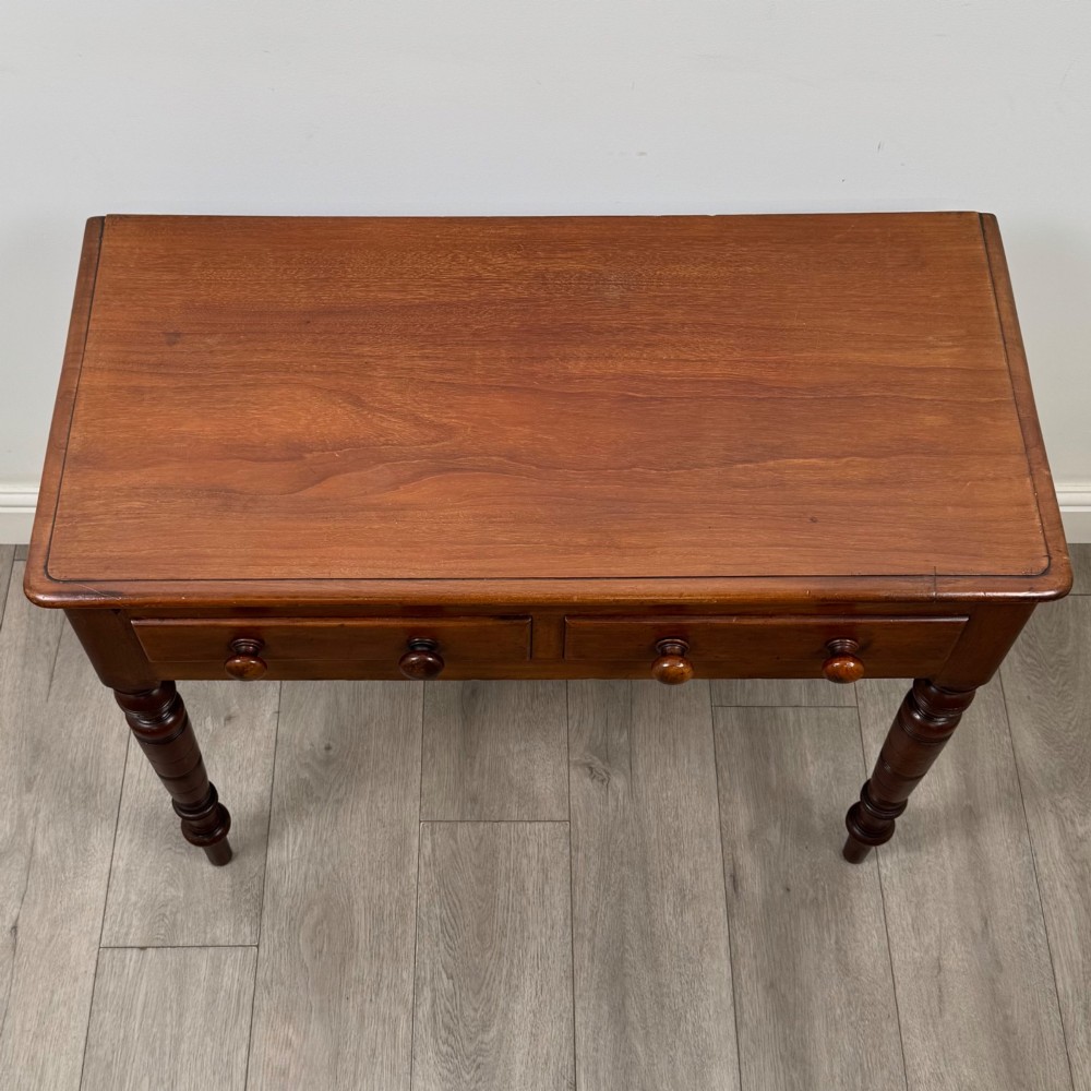 A Victorian mahogany writing table featuring two frieze drawers with wooden knobs and turned reeded legs. View IX