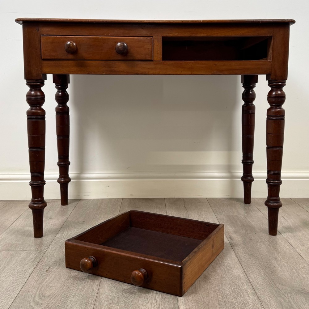A Victorian mahogany writing table featuring two frieze drawers with wooden knobs and turned reeded legs. View X