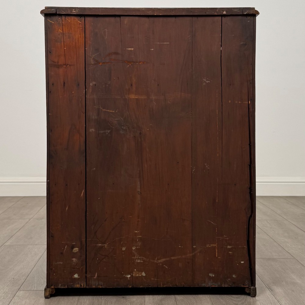 A small Victorian mahogany double-door cupboard featuring raised central panels, green circular brass flower mounts, and a decorative central keyhole. View VI