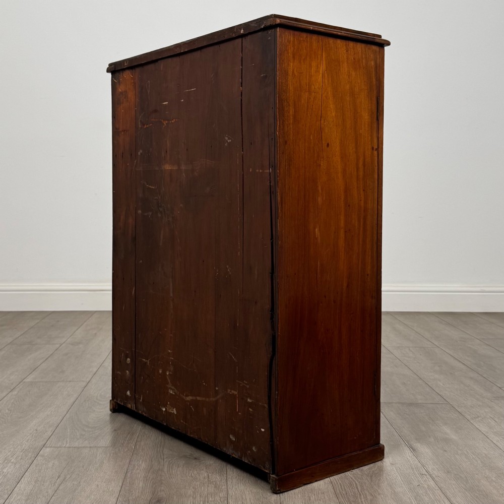 A small Victorian mahogany double-door cupboard featuring raised central panels, green circular brass flower mounts, and a decorative central keyhole. View VII