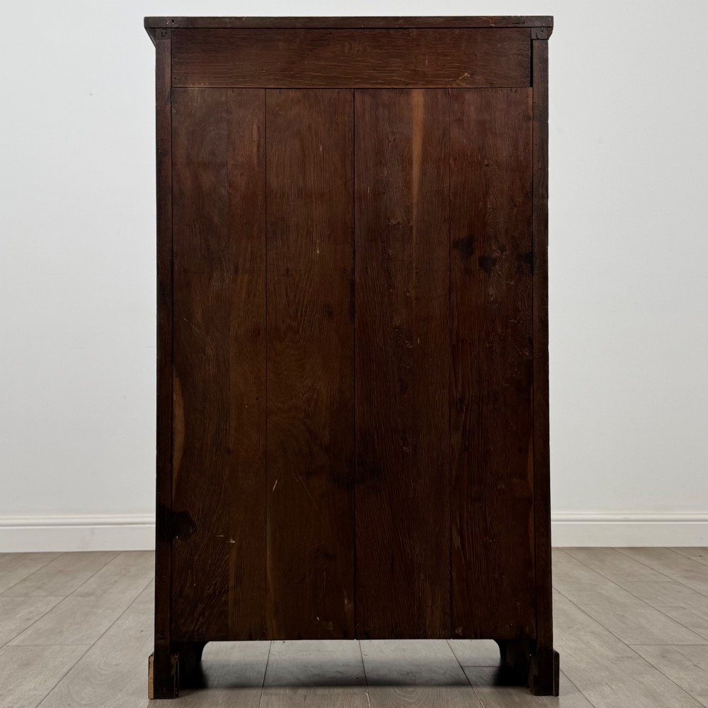 An Edwardian open oak bookcase featuring three interior fixed shelves, dark timber finish, carved moulding on top uprights, and a shaped plinth base. View VI