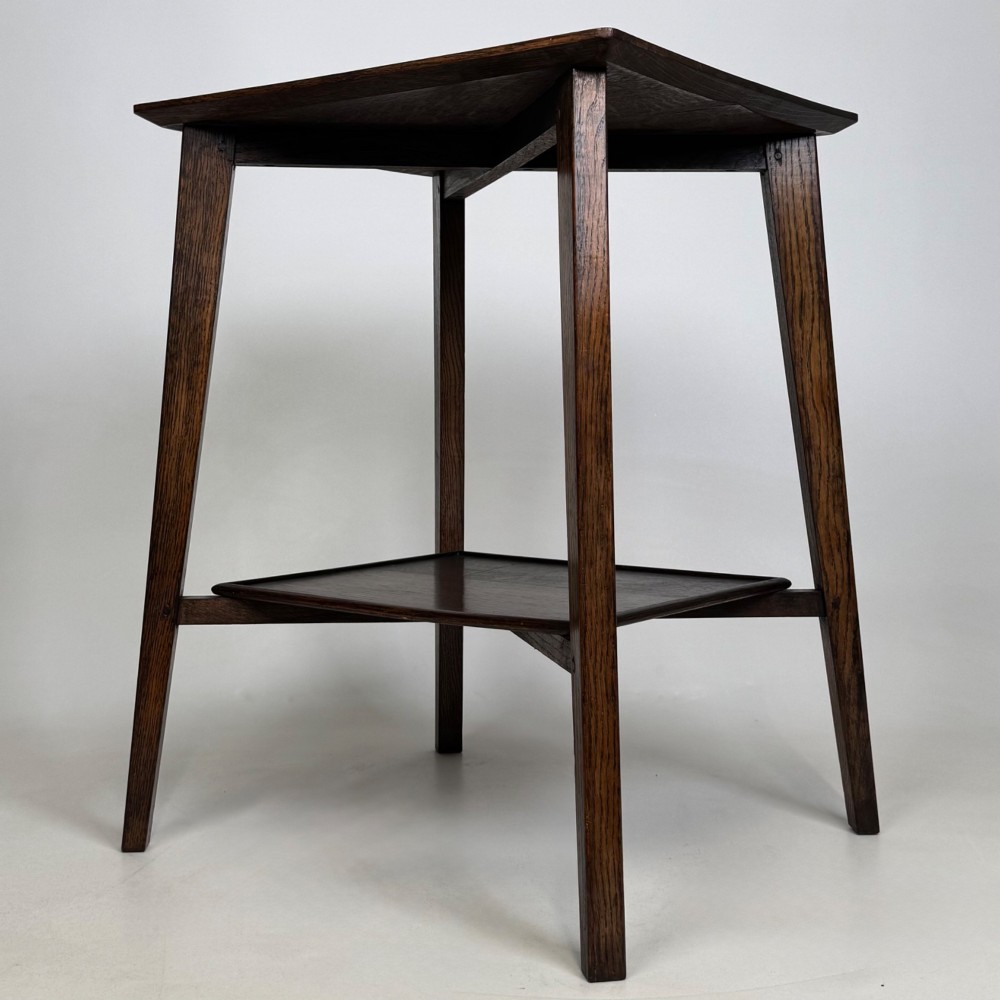 An Edwardian dark oak side table featuring a square top, cross-stretchers, tapered legs, and a lower square shelf. View II
