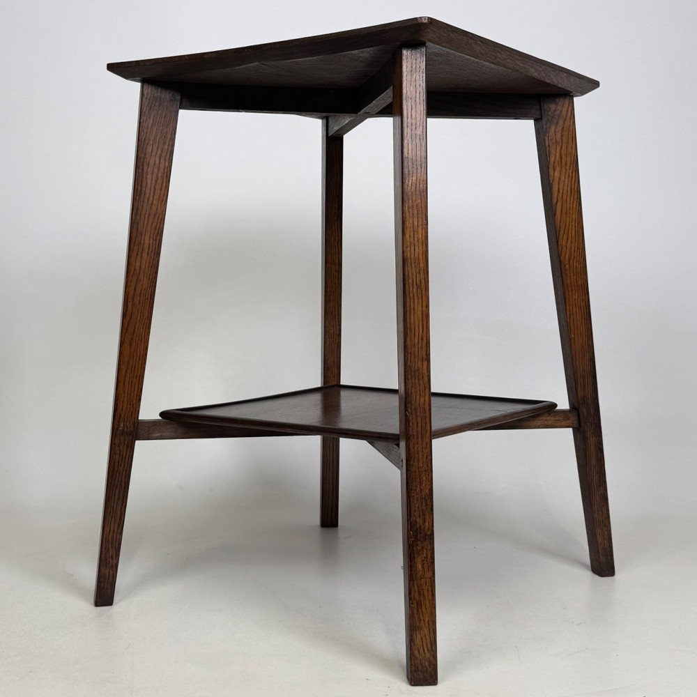 An Edwardian dark oak side table featuring a square top, cross-stretchers, tapered legs, and a lower square shelf. View IV
