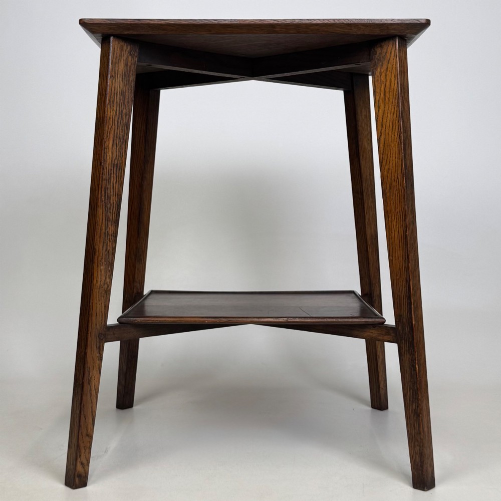 An Edwardian dark oak side table featuring a square top, cross-stretchers, tapered legs, and a lower square shelf. View V