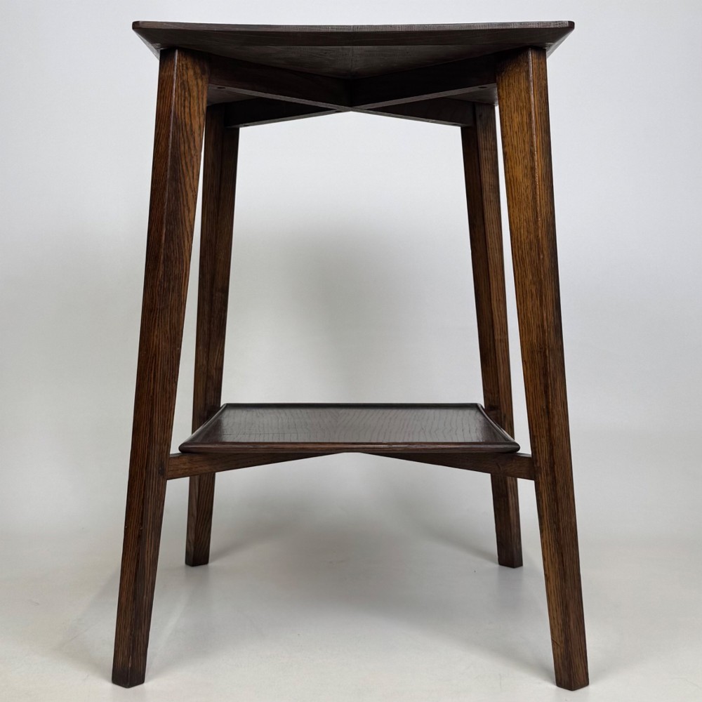 An Edwardian dark oak side table featuring a square top, cross-stretchers, tapered legs, and a lower square shelf. View VII