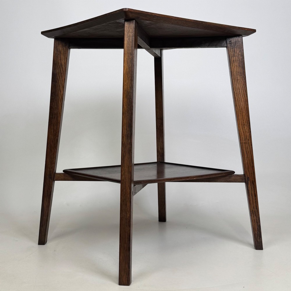 An Edwardian dark oak side table featuring a square top, cross-stretchers, tapered legs, and a lower square shelf. View VIII